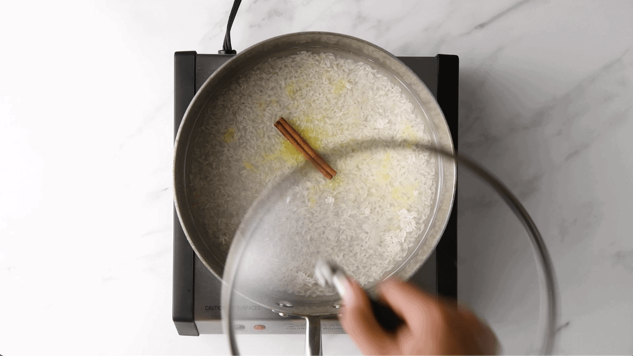 cooking rice for arroz con leche with cinnamon and lemon zest