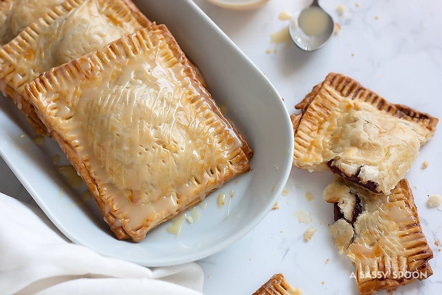 These semi-homemade guava and cream cheese pop tarts are super easy to make using refrigerated pie crust and condensed milk for drizzling. The perfect combination of a Cuban treat on an American classic.