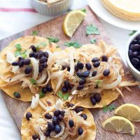 Using leftovers or shredded rotisserie chicken, make these Crispy Chicken Tacos, vaca frita style, topped with sautéed onions and black beans!