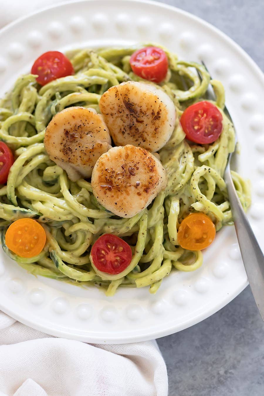 Zucchini noodles topped with a avocado sauce and seared scallops