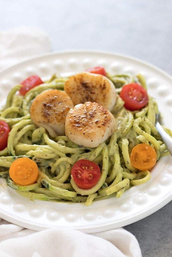 Zucchini noodles topped with a avocado sauce and seared scallops