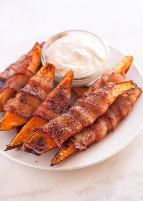 Sweet potatoes cut into fries, seasoned with salt, pepper, and smoked paprika, then wrapped in uncured applewood smoked bacon and baked to perfection!