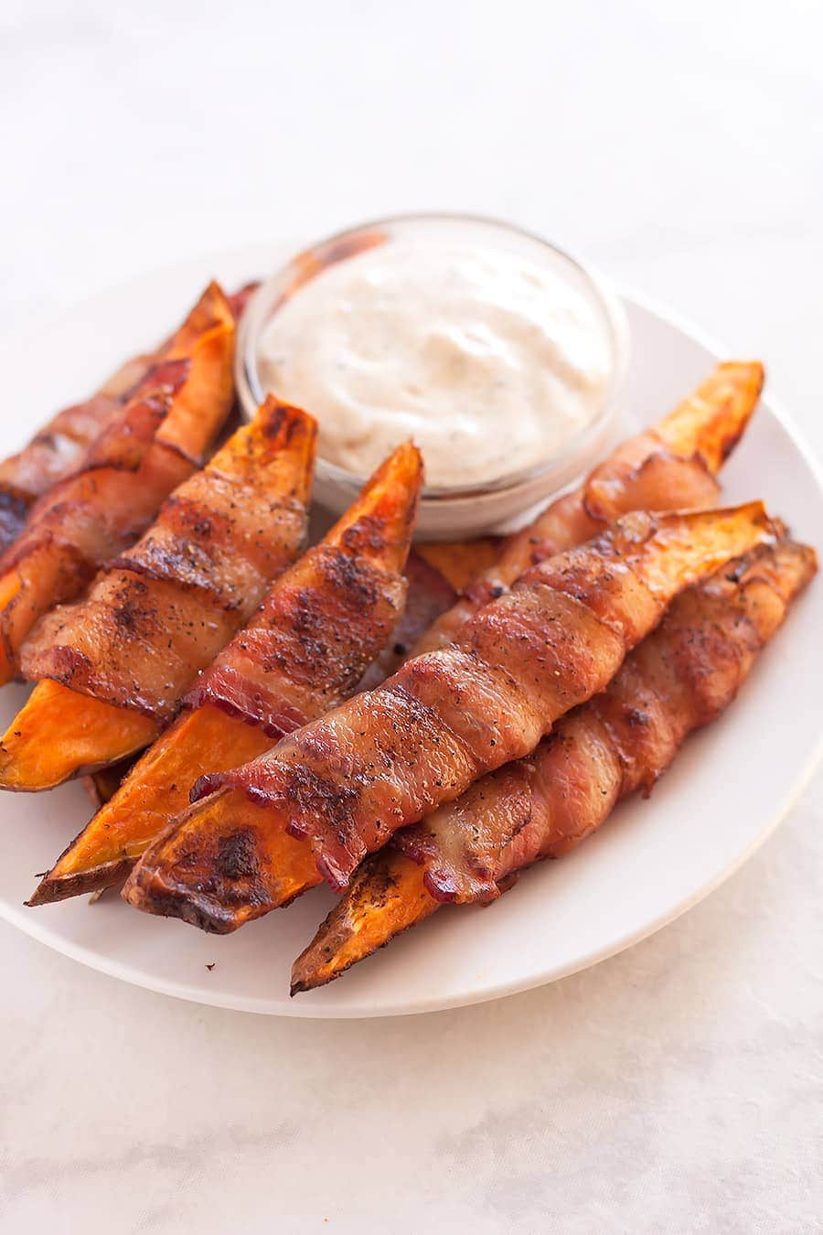 Sweet potatoes cut into fries, seasoned with salt, pepper, and smoked paprika, then wrapped in uncured applewood smoked bacon and baked to perfection!