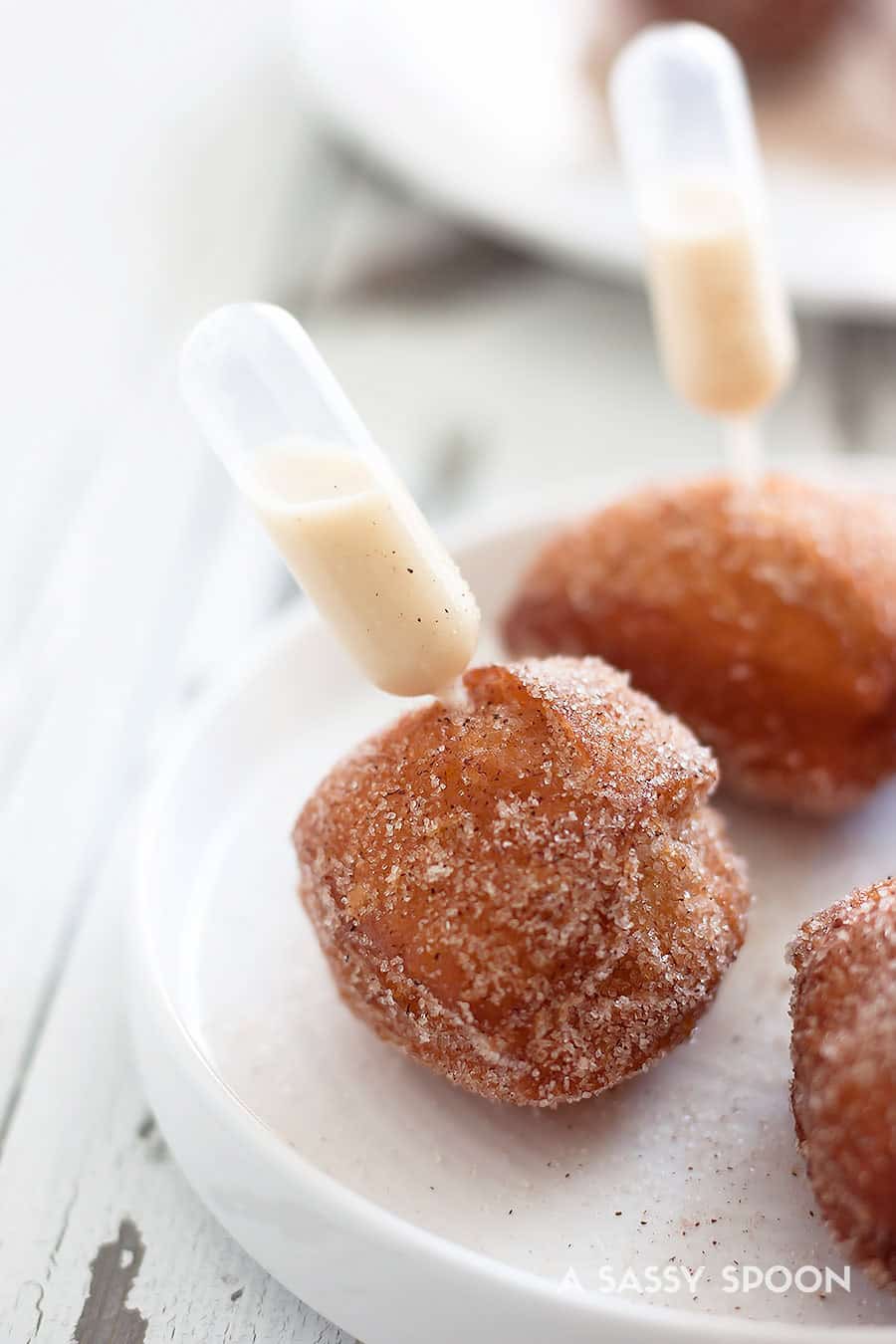 Pipette filled with eggnog that's inserted into a donut hole