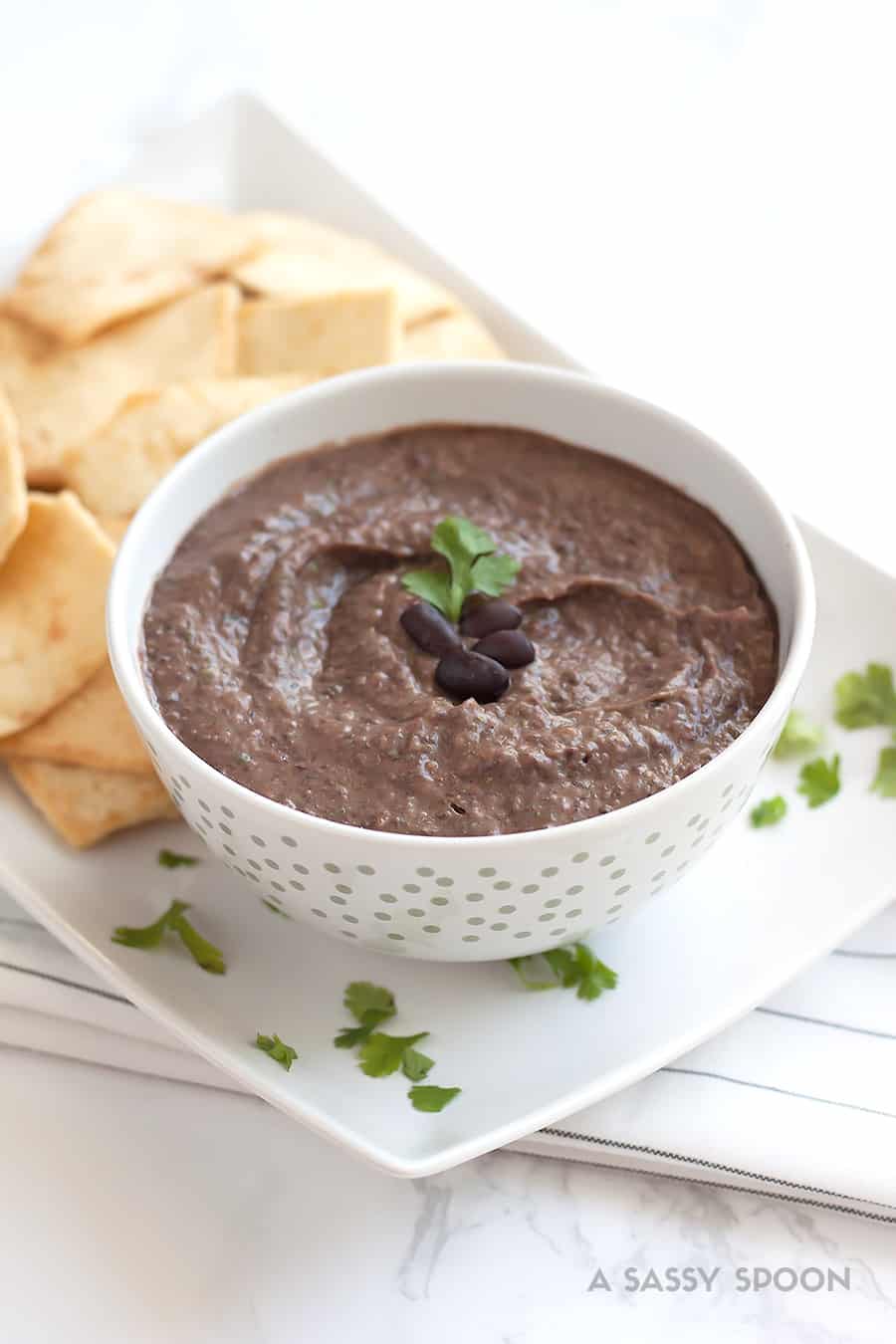 Black bean hummus served with pita chips on white tray