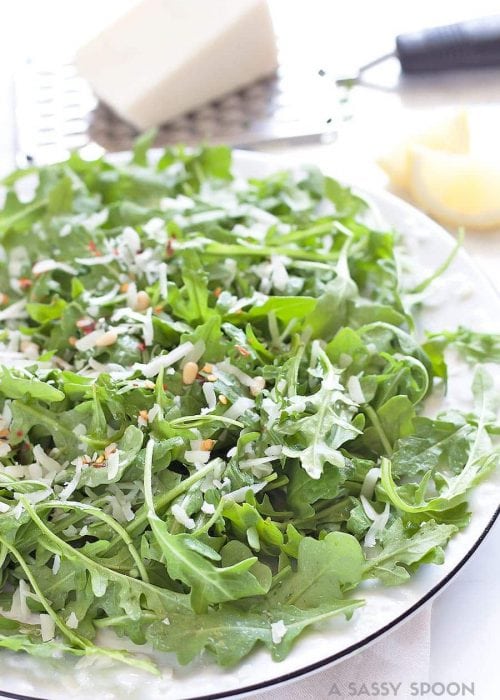 a plate of arugula with pine nuts, lemon dressing, red chili flakes and pecorino