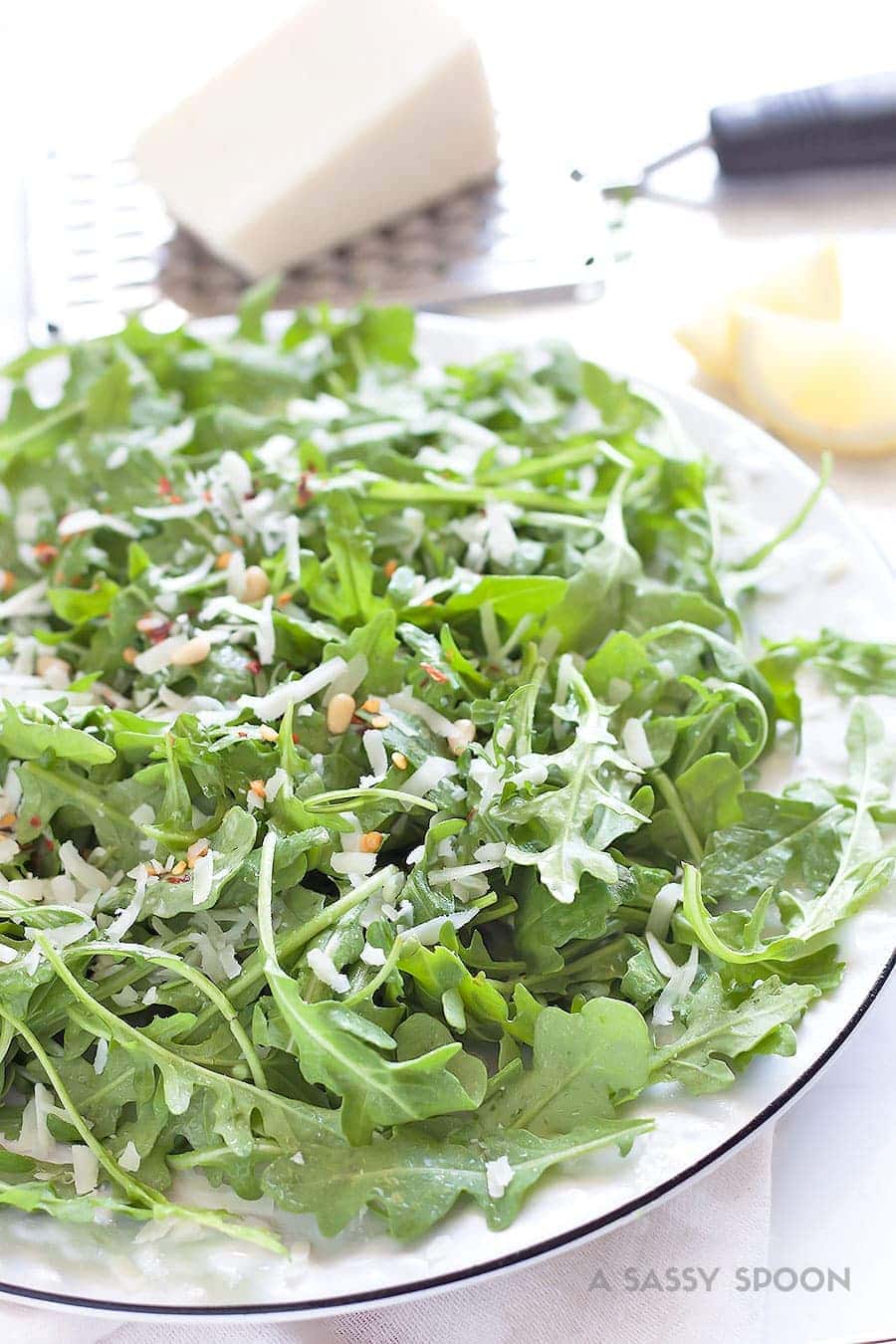 a plate of arugula with pine nuts, lemon dressing, red chili flakes and pecorino 