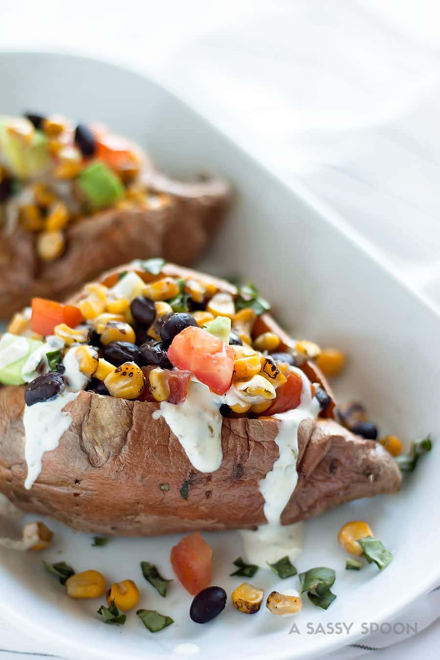 Baked Vegetarian Stuffed Sweet Potatoes. Baked sweet potatoes loaded with roasted corn, black beans, chopped tomatoes, diced onions, and avocado result in a meatless, flavorful and easy 20-minute meal for busy weeknights!