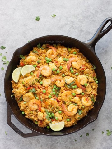Brown rice, chicken, shrimp, and turmeric placed in an iron skillet