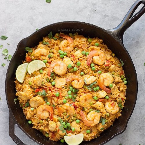 Brown rice, chicken, shrimp, and turmeric placed in an iron skillet