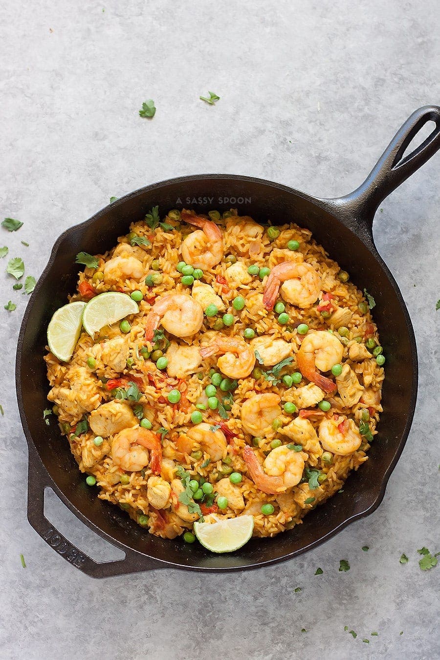 Brown rice, chicken, shrimp, and turmeric placed in an iron skillet