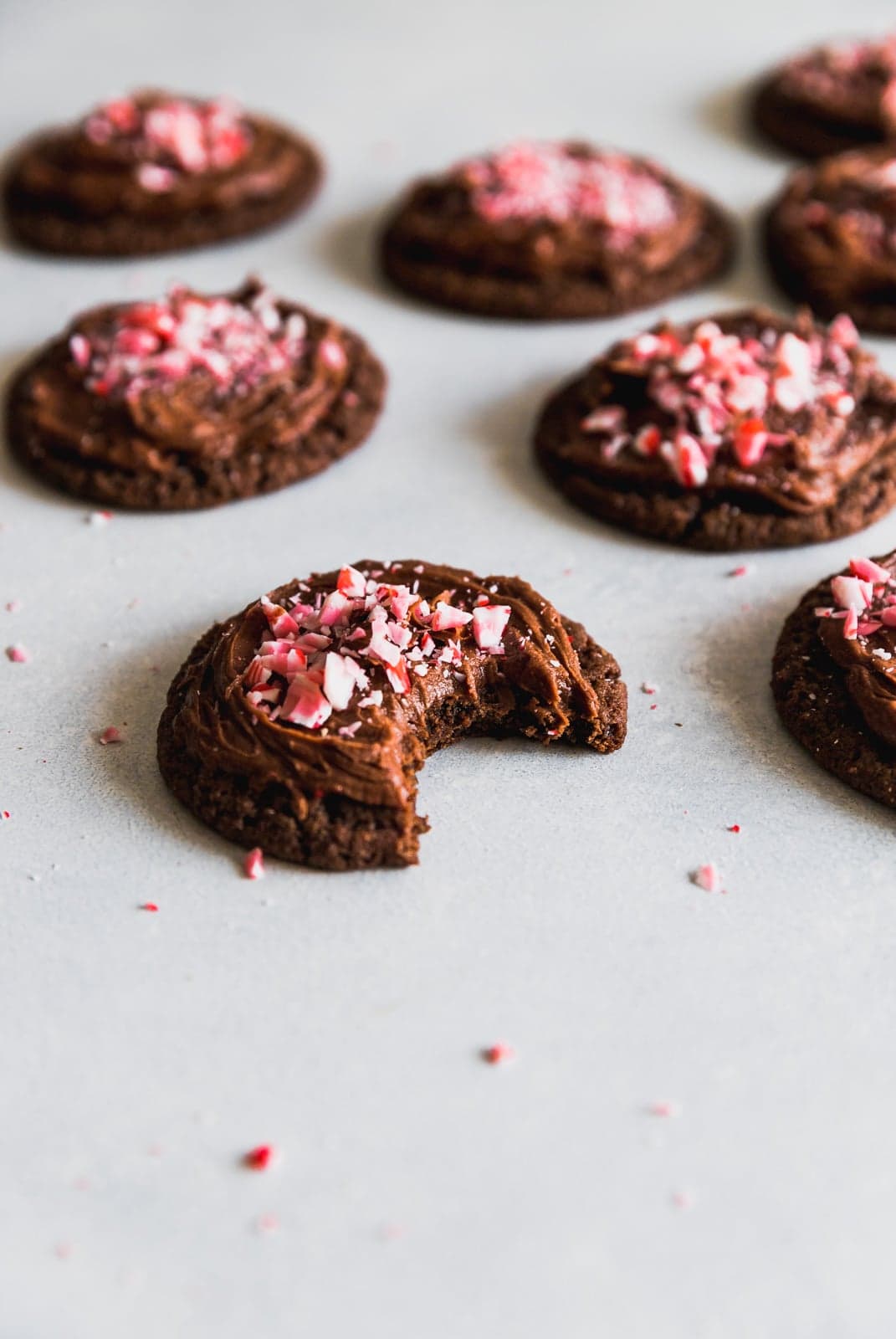 chocolate peppermint cookies on table; one with a bite taken out of it