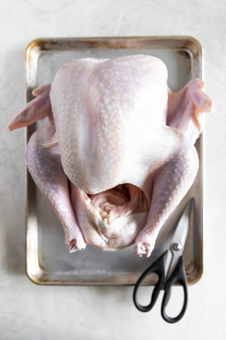 Whole raw chicken on a baking tray with scissors, ready for cooking or roasting. Best for delicious family meals and poultry recipes.