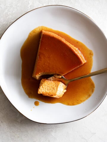 Rich caramel flan dessert with creamy texture and smooth caramel sauce on a white plate.