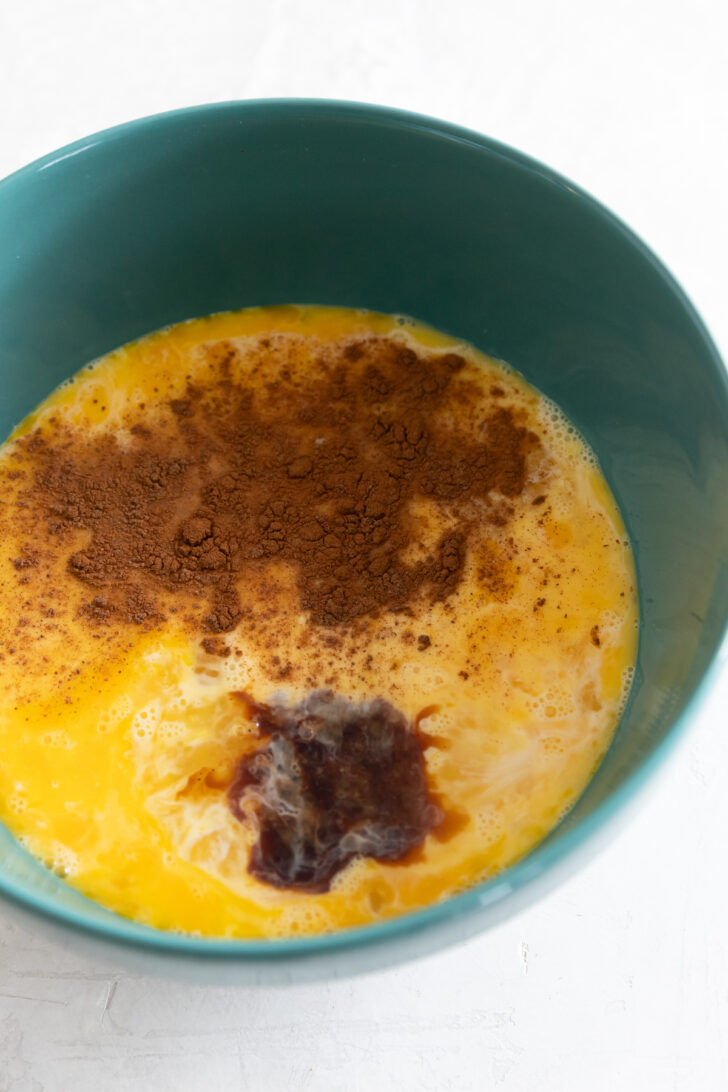 Creamy scrambled eggs with cocoa powder and vanilla in a teal bowl.