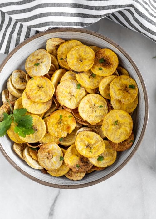 Crispy, salty, baked plantain chips with a vegan garlic dip. The perfect paleo, dairy-free, vegan snack made with just 5-ingredients!