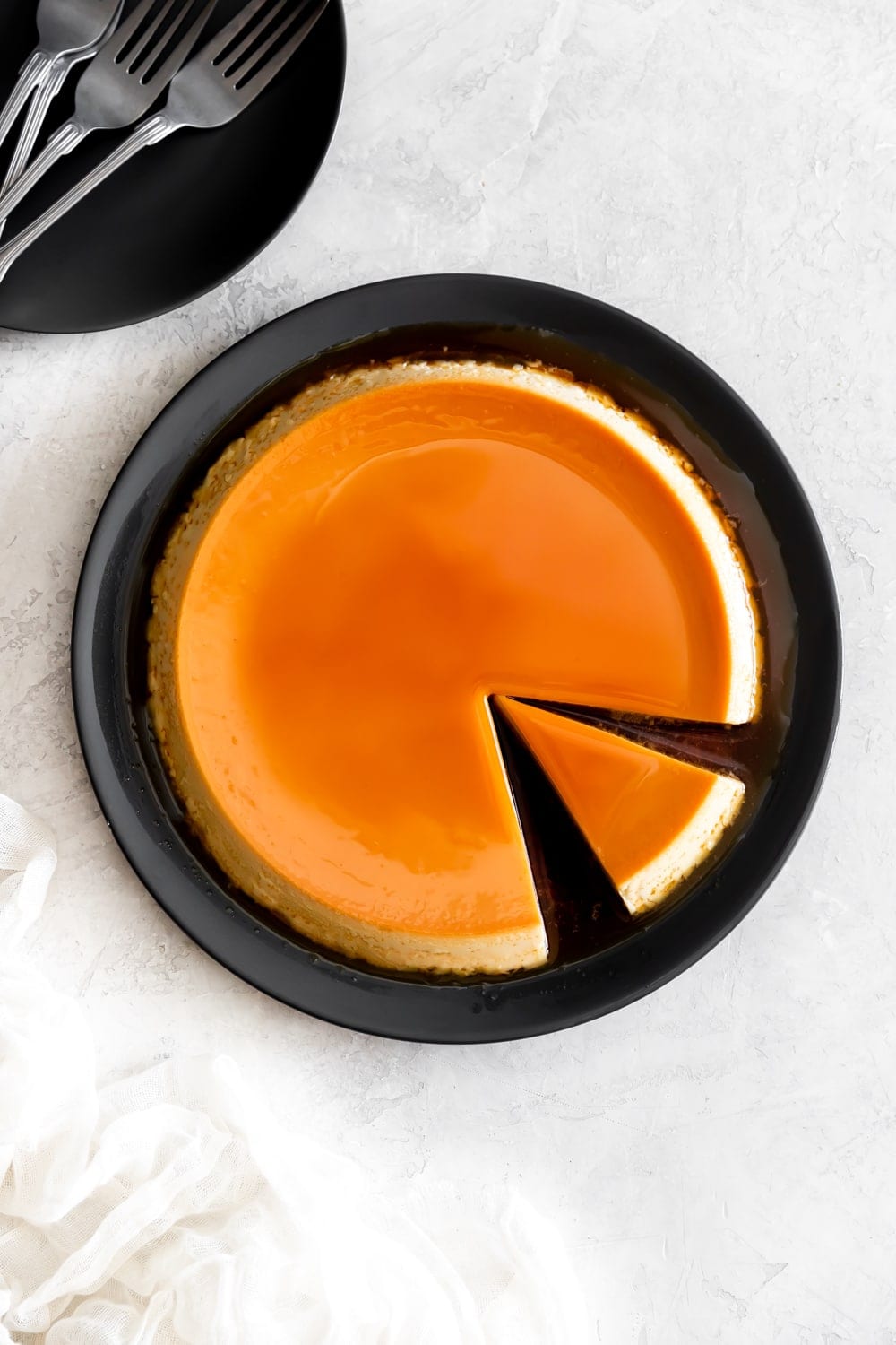 smooth flan de queso with caramel on a dark gray plate