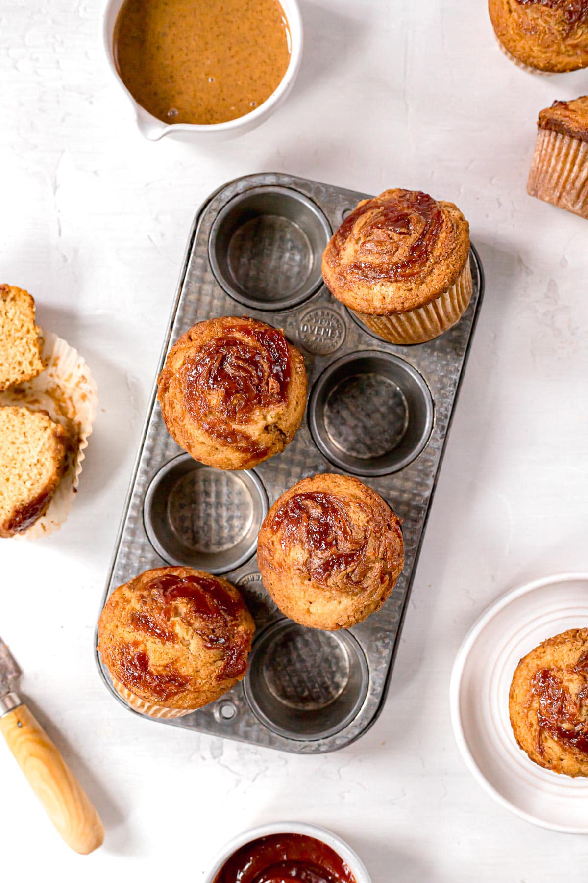 almond butter and guava jelly muffins in a muffin tin on a white surface