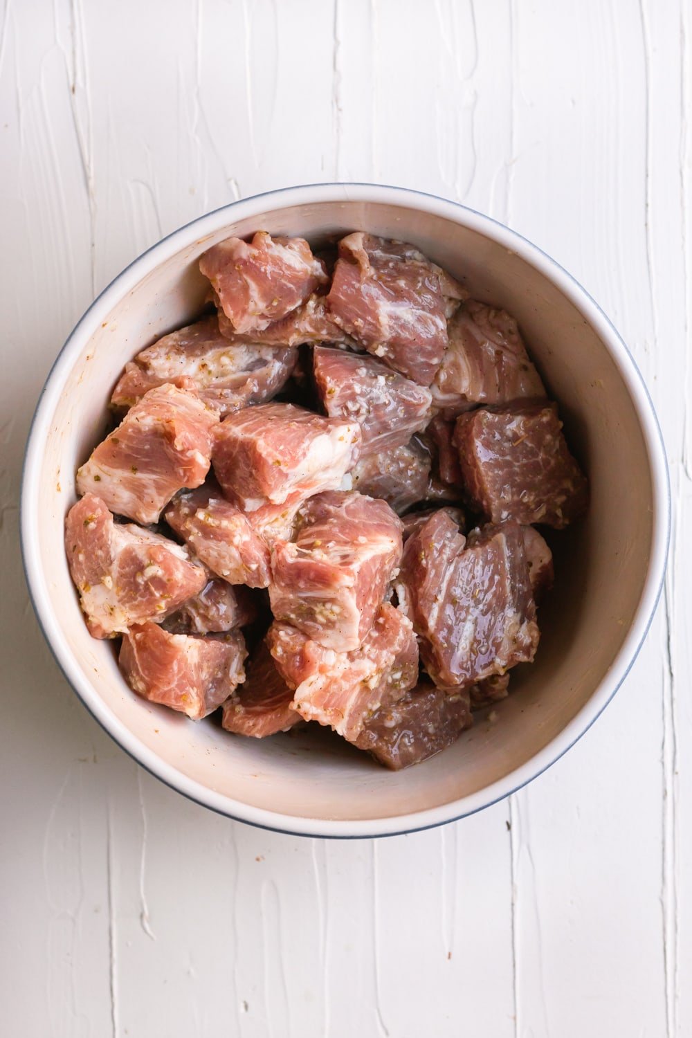 pork chunks in a bowl marinating with sour orange juice, mashed garlic paste, and spices