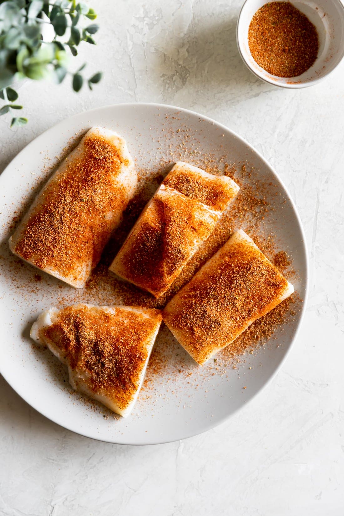 cod fillets on a white plate with smoky seasoning on top