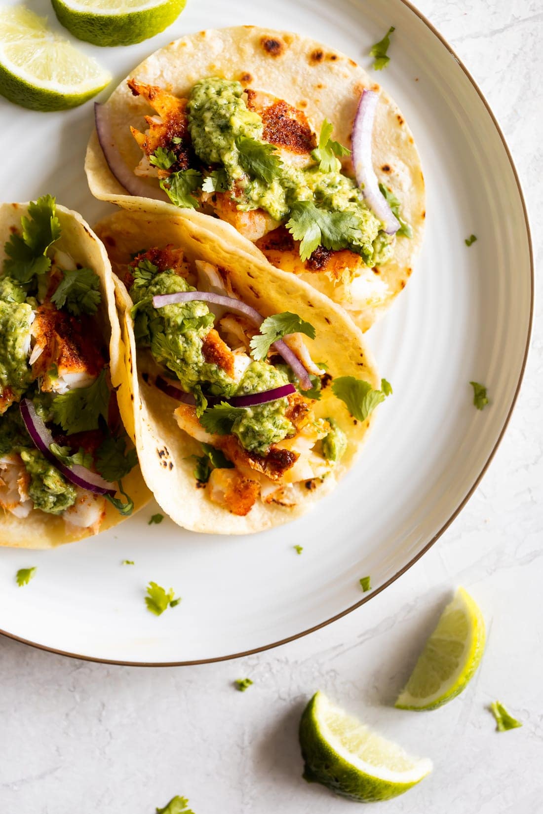 fish tacos on a white plate with avocado chimichurri sauce