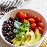 charred tomato salad bowl with sautéed black beans and sliced avocado