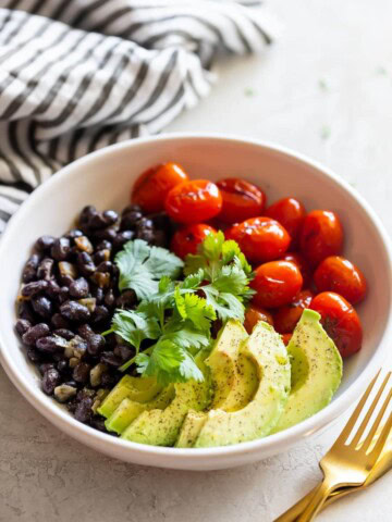 charred tomato salad bowl with sautéed black beans and sliced avocado