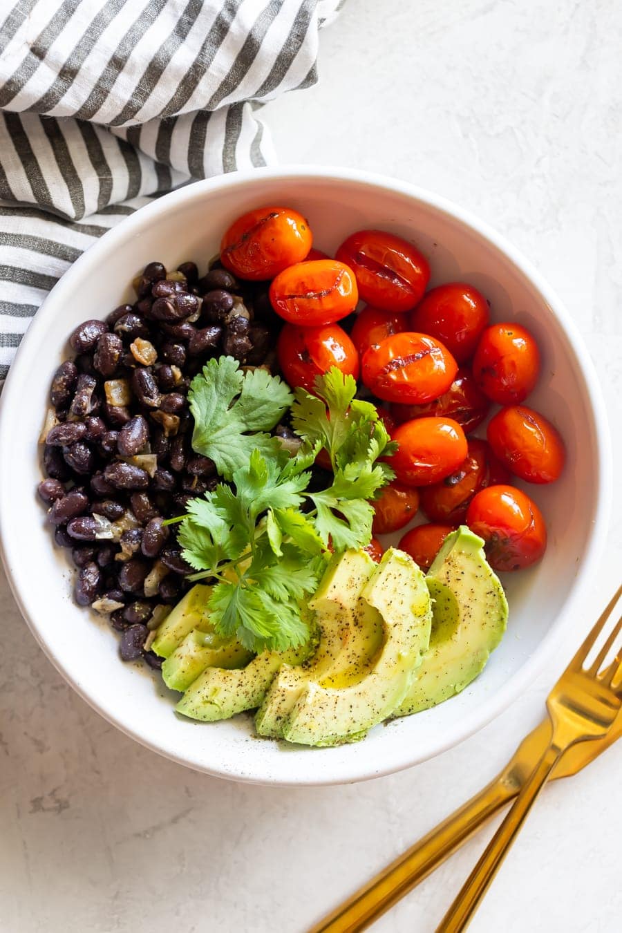 avocado salad bowl with black beans and blistered cherry tomatoes