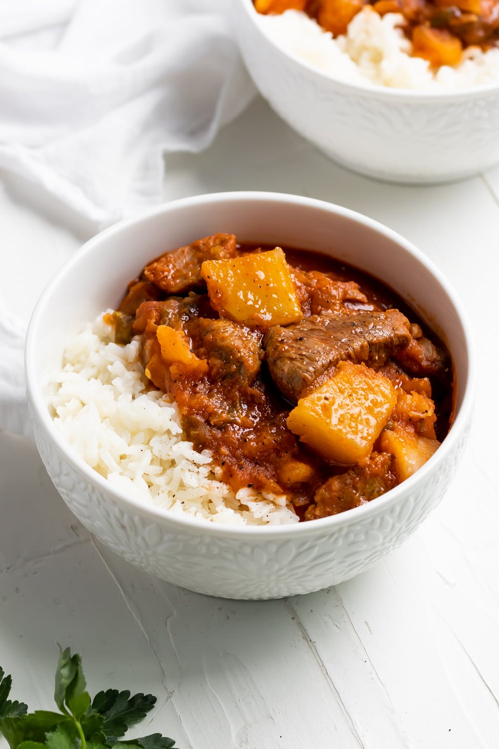 carne con papas with white rice in a white bowl on a white table