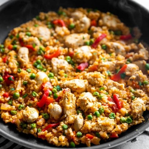 Classic arroz con pollo gets a low-carb makeover by using riced cauliflower instead of rice! Quick + flavorful weeknight meal for any day of the week!