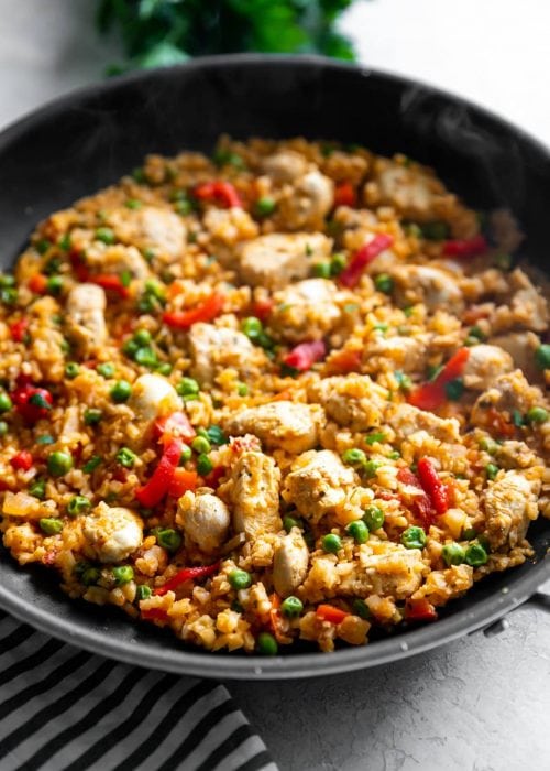 Classic arroz con pollo gets a low-carb makeover by using riced cauliflower instead of rice! Quick + flavorful weeknight meal for any day of the week!