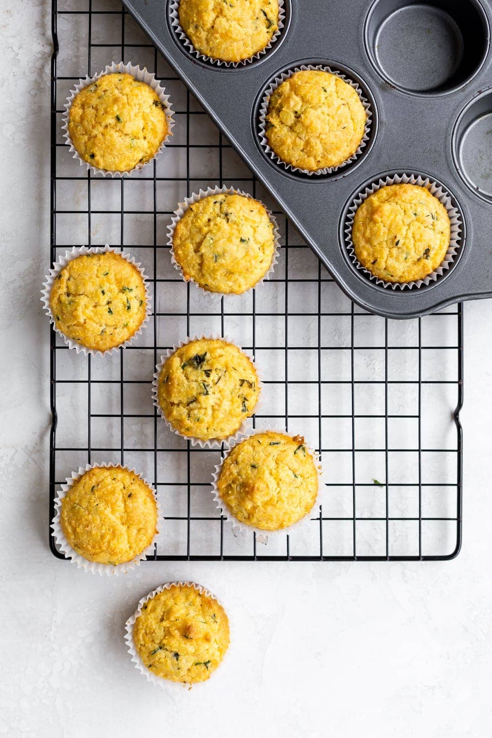 corn muffins in a muffin tin with cornmeal, chives, and fresh thyme 