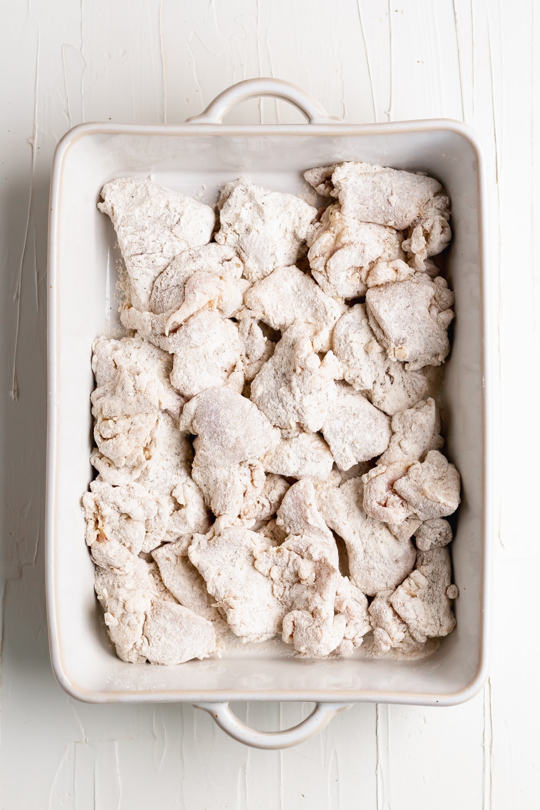 chicken thighs chunks coated in flour in a baking dish