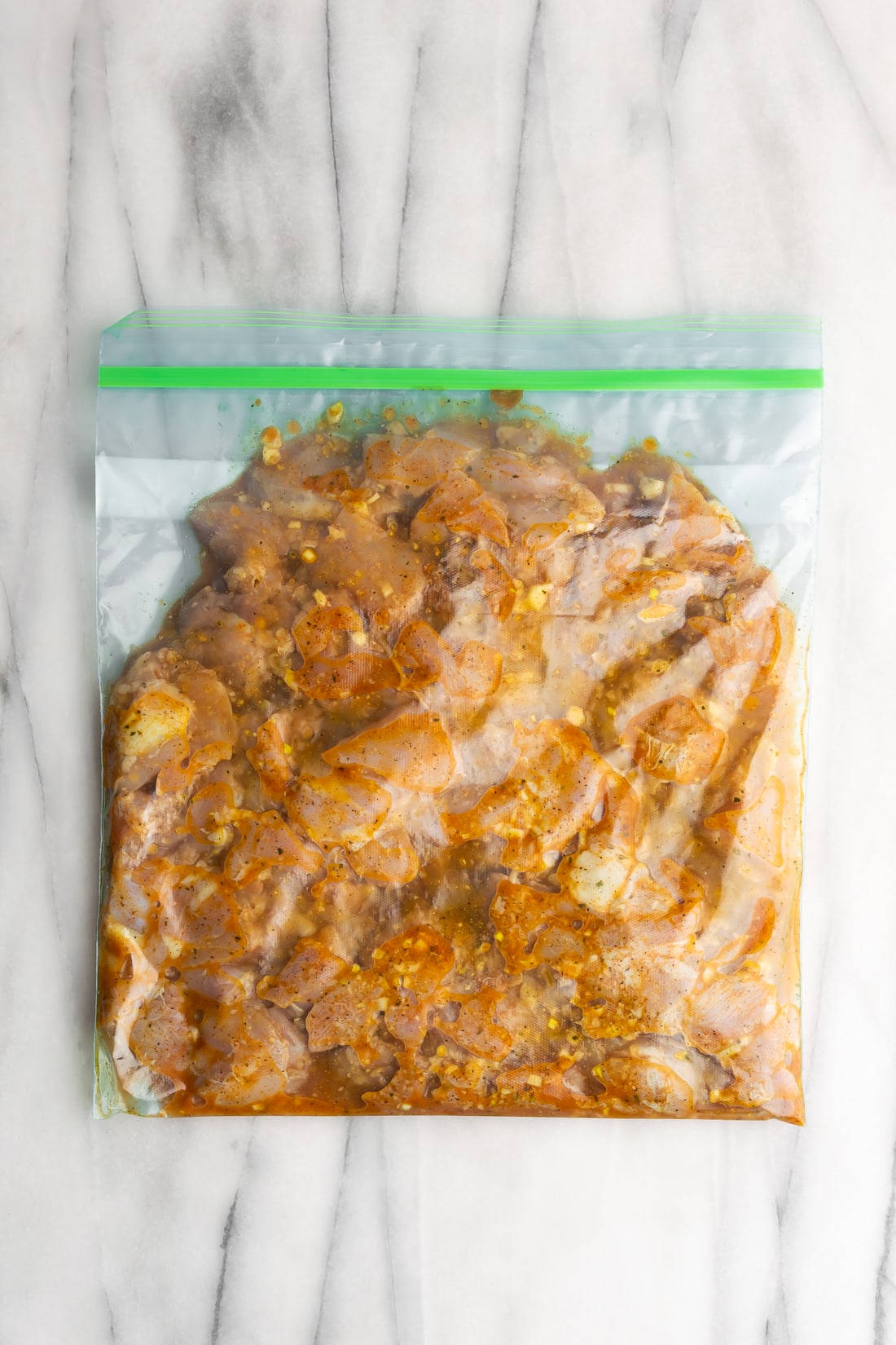 chicken chunks marinating in citrus marinade with sazon completa in a resealable bag