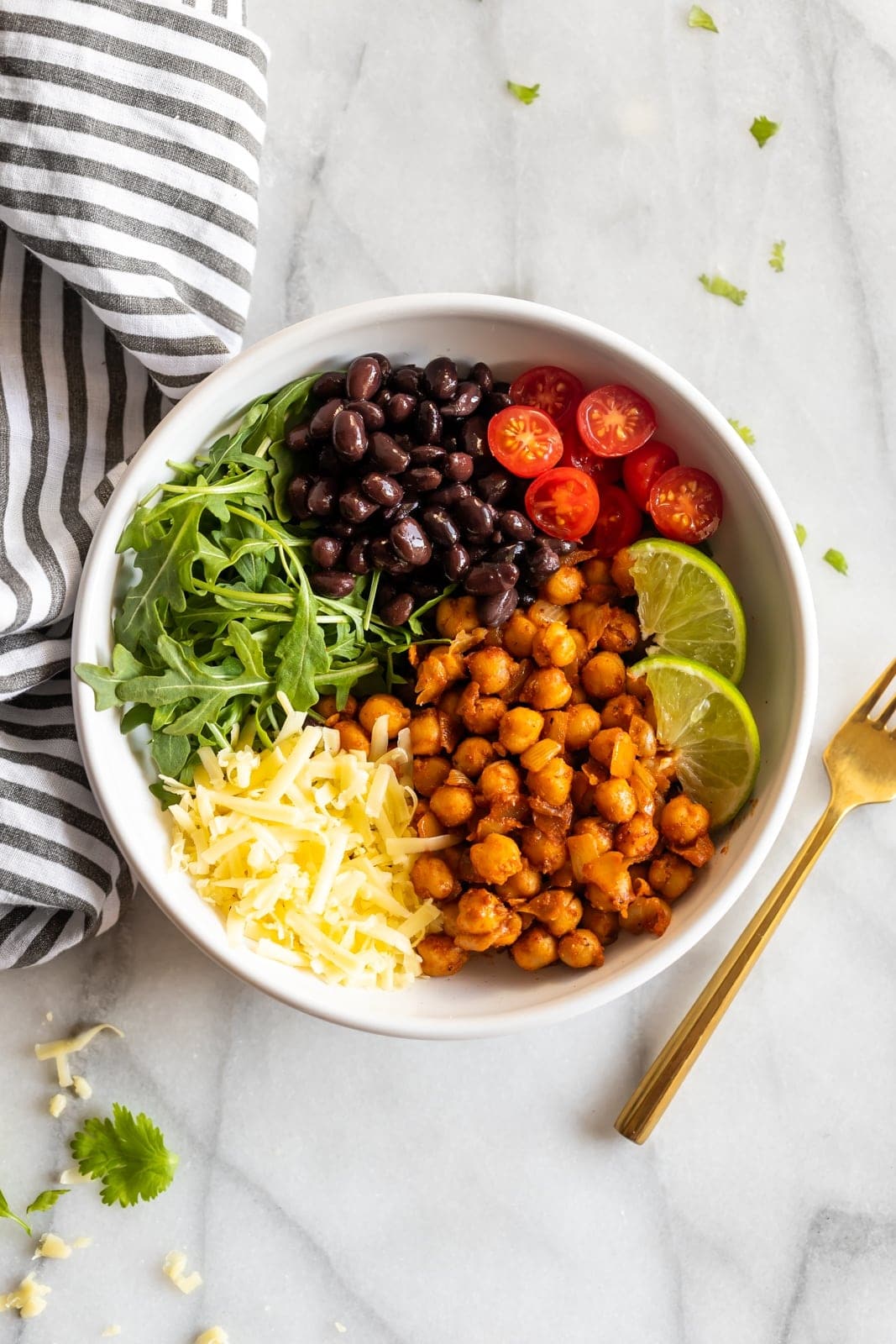 Vegetarian taco bowls made with spicy, smoky chipotle chickpeas, black beans, arugula, shredded cheese, and chopped cherry tomatoes!