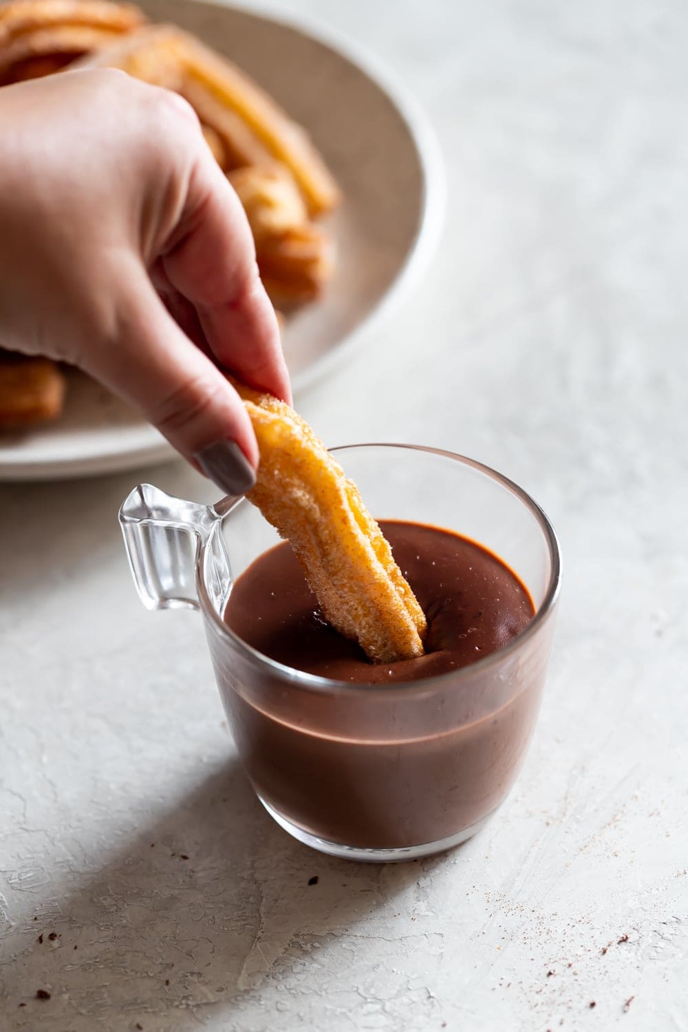photo of a churro being dipped into thick, hot chocolate