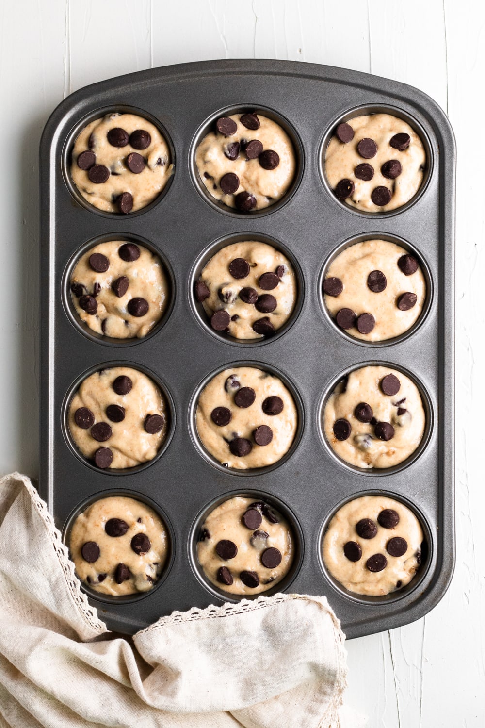 batter in 12 cup muffin tin with chocolate chips on top before baking