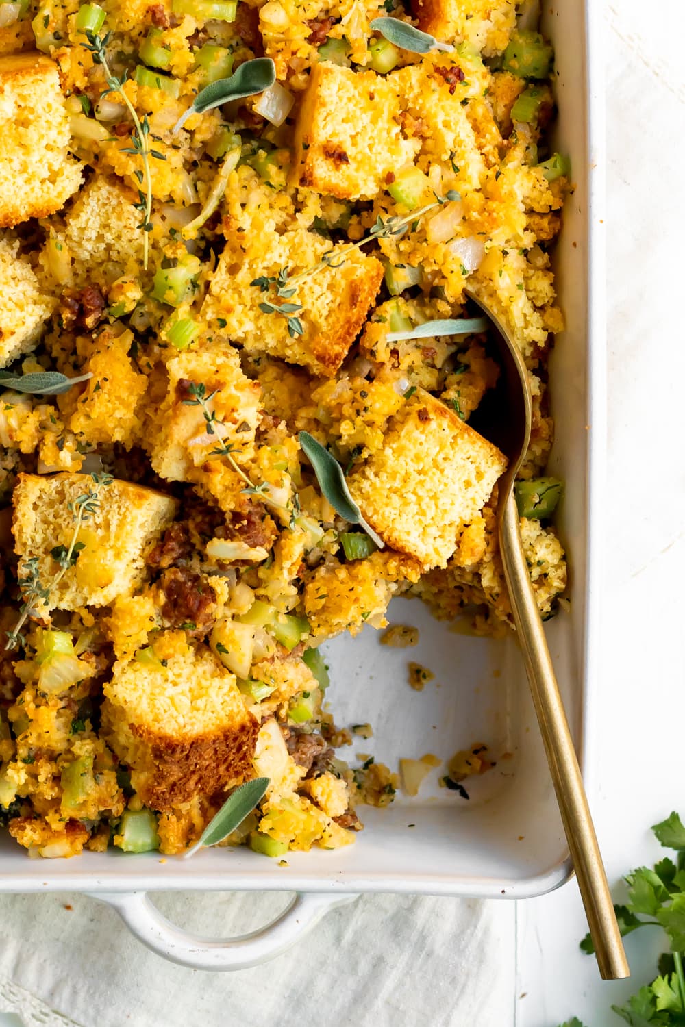 cornbread stuffing with chorizo in a baking dish with a serving spoon