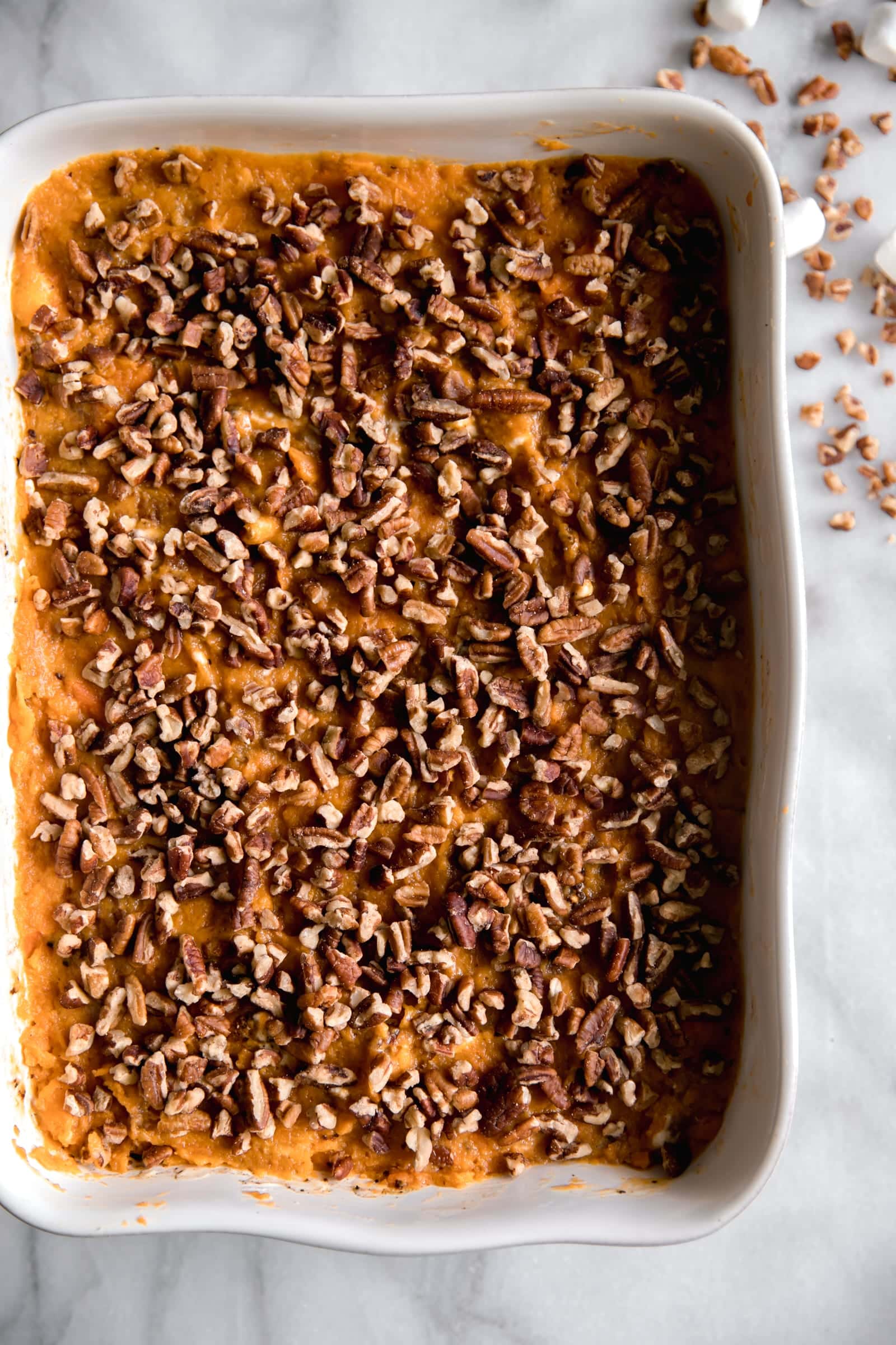 mashed sweet potato with chopped pecans on top in a casserole dish