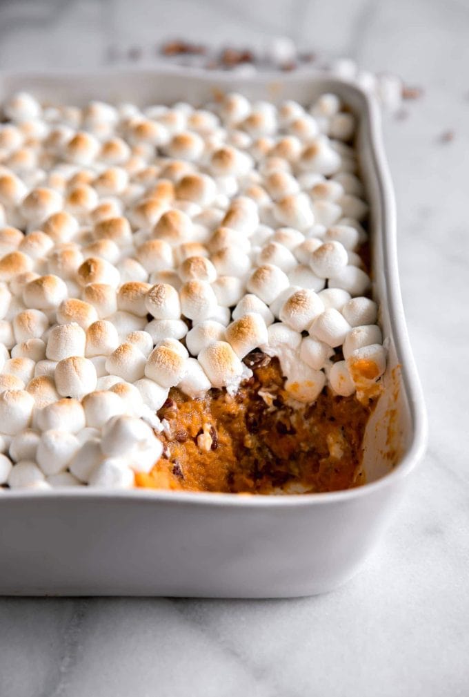 mashed sweet potato with toasted marshmallows on top in a casserole dish with a spoonful missing