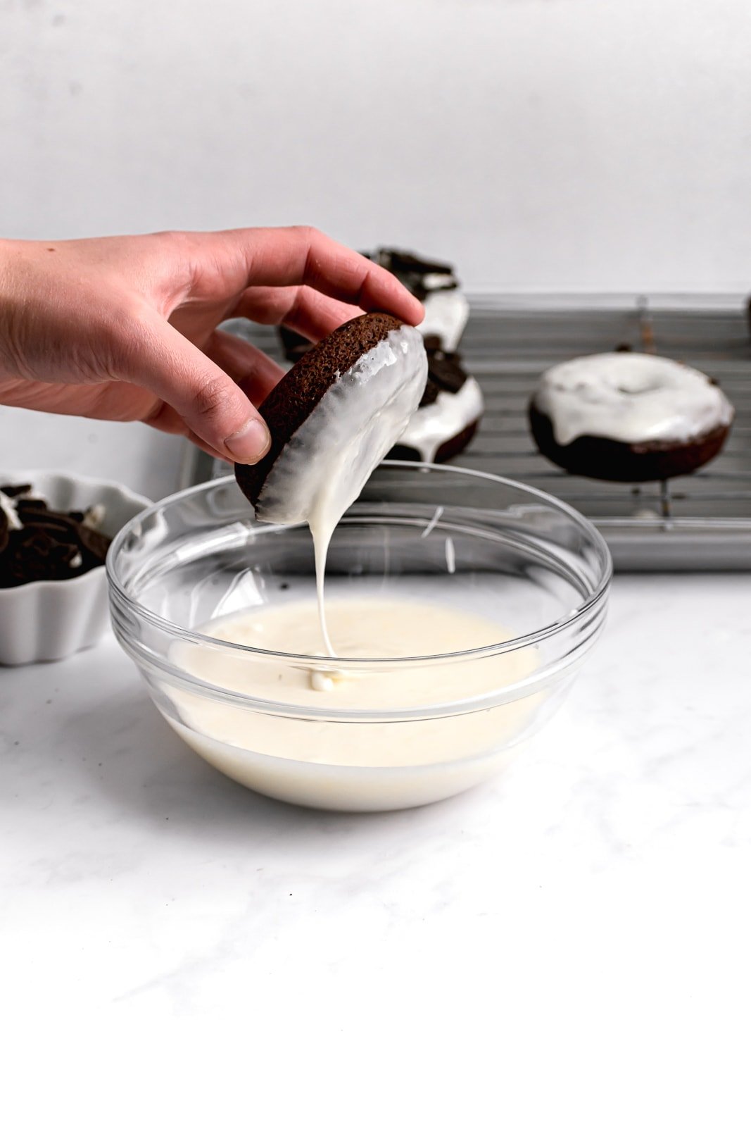 chocolate donuts being dipped in a thick cream cheese icing