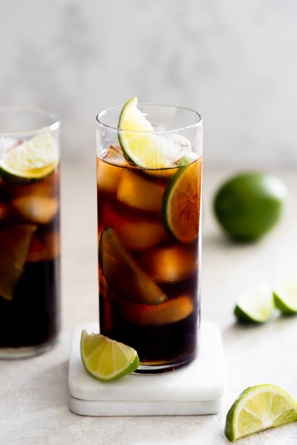 rum and coke in a highball glass with ice and lime wedges