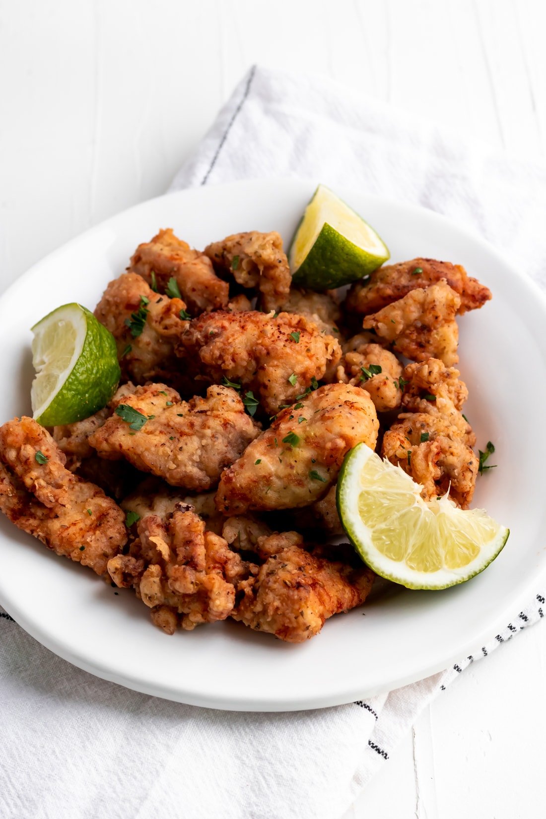 chicharron de pollo on a plate with lime wedges