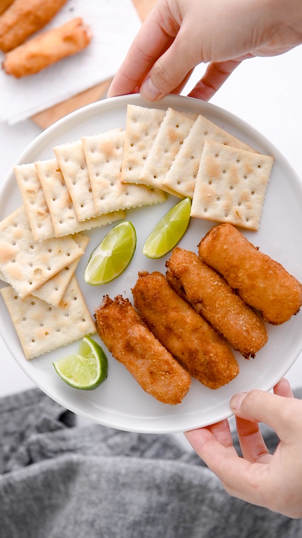 ham croquetas with saltines and lime wedges on a white plate