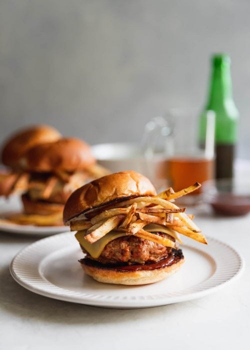 A Cuban-inspired burger made with ground turkey, chorizo, chopped onions, spices, melted gruyere, homemade shoestring potatoes, and guava BBQ sauce served on toasted hamburger buns.