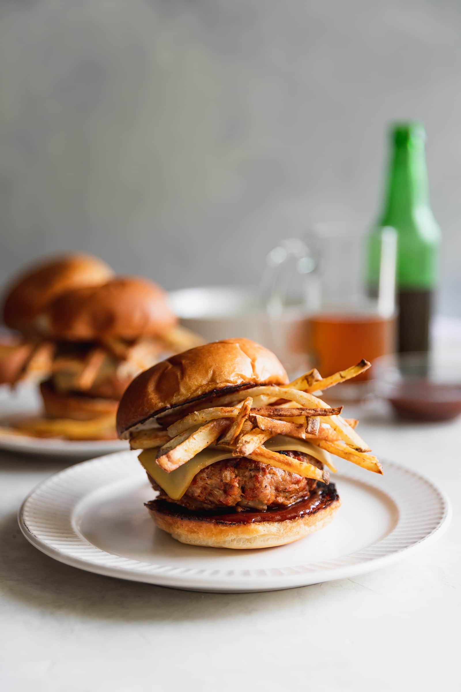 A Cuban-inspired burger made with ground turkey, chorizo, chopped onions, spices, melted gruyere, homemade shoestring potatoes, and guava BBQ sauce served on toasted hamburger buns.