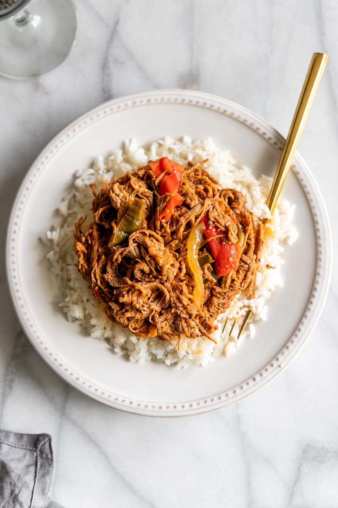 ropa vieja served over white rice on a white plate