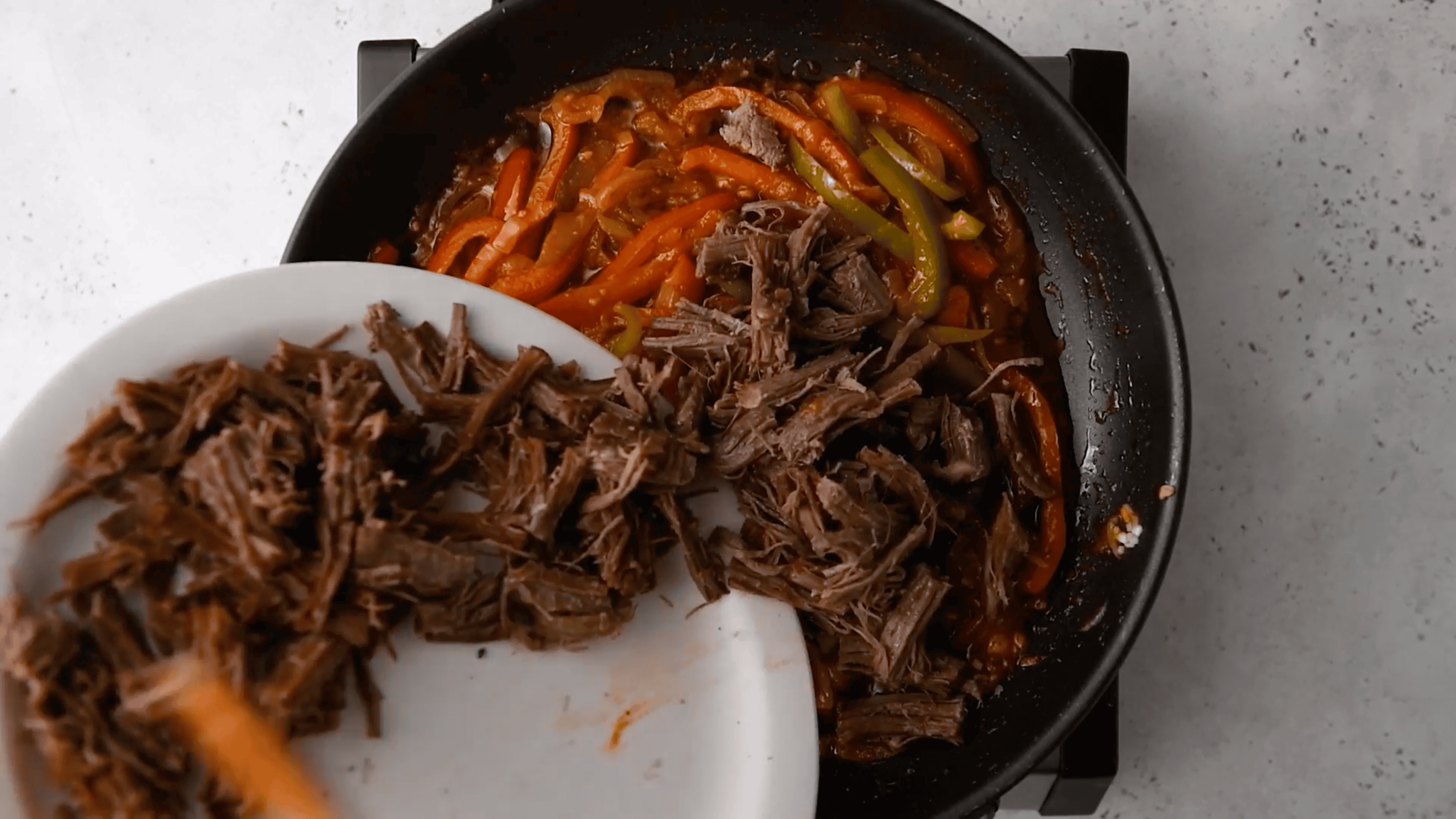 adding shredded beef with the Cuban sofrio in a skillet
