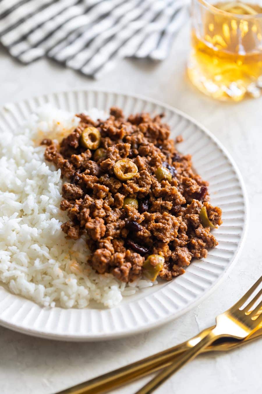 cuban picadillo with olives and raisins served on top of white rice on a white plate