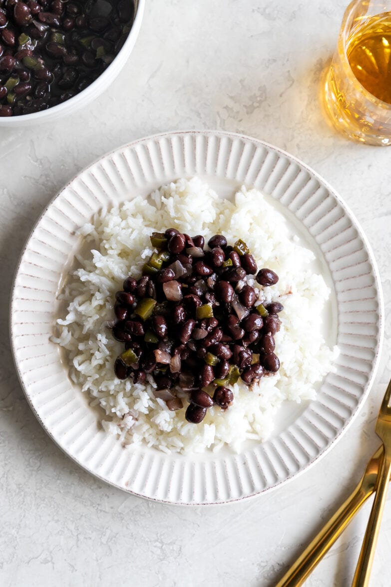 arroz con frijoles - white rice with cuban black beans on top on a white place